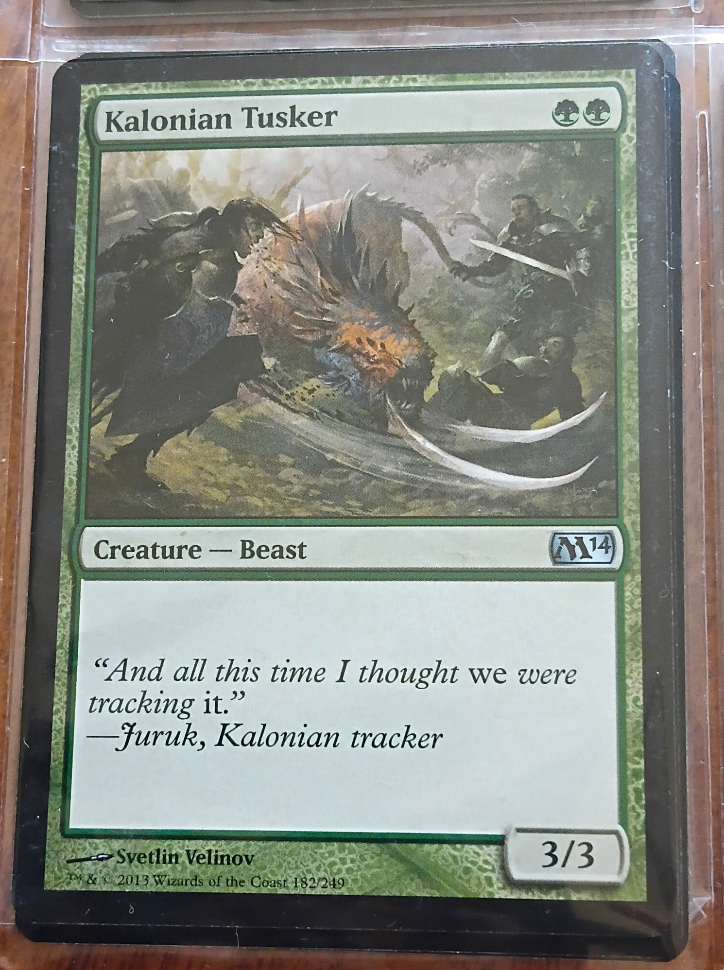 Trading card featuring a Kalonian Tusker with artwork and text on a wooden surface.