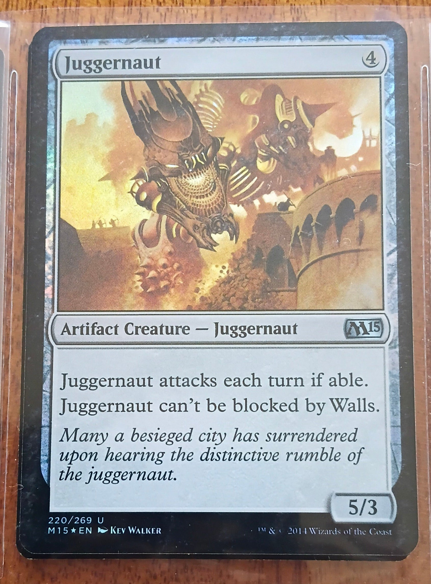 Trading card featuring a creature named 'Juggernaut' on a wooden surface.